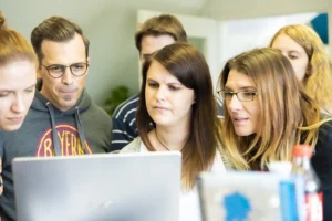 Work colleagues look intently at a laptop screen.